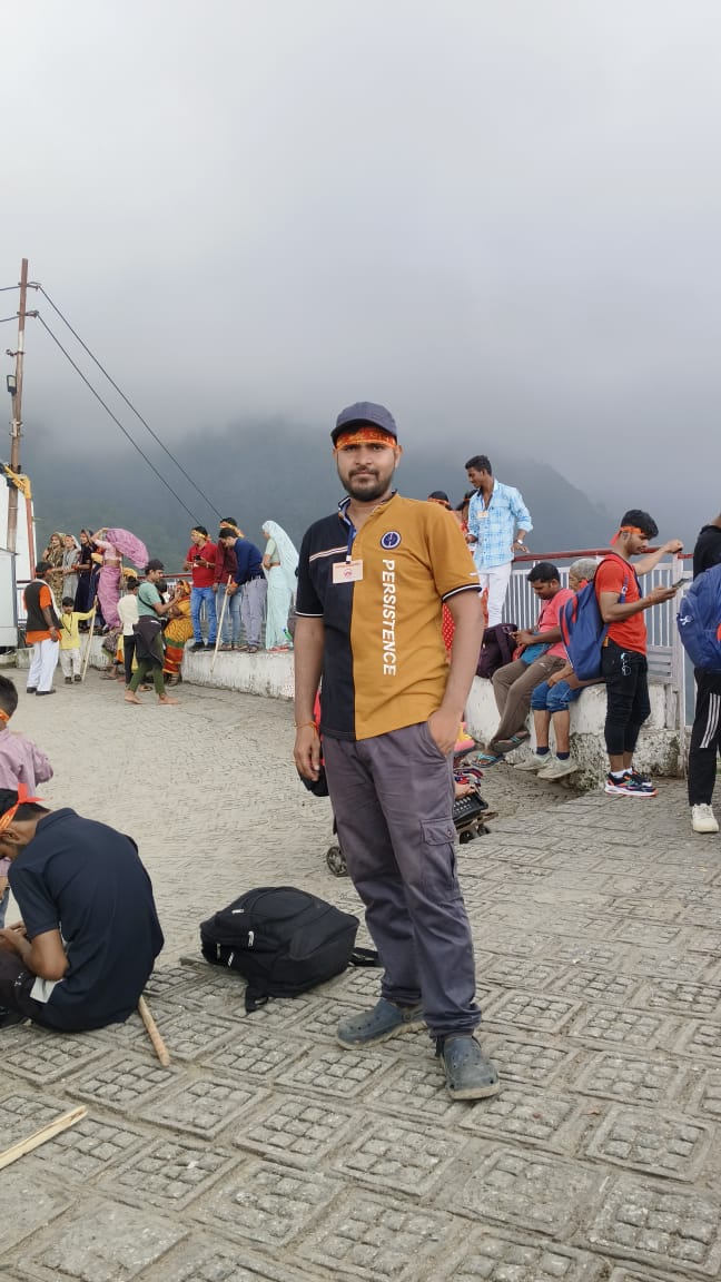 A young man in glasses writes in a notebook while sitting on a stylish couch indoors.